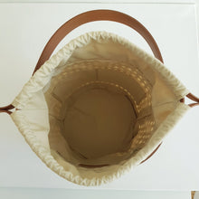 Lataa kuva Galleria-katseluun, Tyylikäs ja tilava ASYA Bucket nahkalaukku raffiareunalla ja polyesterivuorella. Laukussa hyvin tilaa isomallekkin tavaralle. Koko: 20 cm halkaisija, 24 cm korkeus Olkahihnan leveys 1,5 cm, pituus 103 cm Materiaali: nahka/ raffia/ polyesterivuori Valmistusmaa: Italia