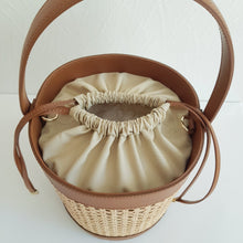 Lataa kuva Galleria-katseluun, Tyylikäs ja tilava ASYA Bucket nahkalaukku raffiareunalla ja polyesterivuorella. Laukussa hyvin tilaa isomallekkin tavaralle. Koko: 20 cm halkaisija, 24 cm korkeus Olkahihnan leveys 1,5 cm, pituus 103 cm Materiaali: nahka/ raffia/ polyesterivuori Valmistusmaa: Italia