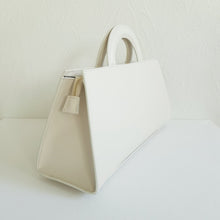 Lataa kuva Galleria-katseluun, ALIINA nahkalaukku kantokahvoilla ja säädettävällä olkahihnalla. Edestä laukkua koristaa kaunis kullanvärinen solkiyksityiskohta.