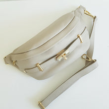 Lataa kuva Galleria-katseluun, Upea tyyliltään ja käytännöllinen kooltaan ALICE crossbody vyö-olkalaukku. Laukussa on säädettävä hihna, kullanväriset metalliosat, vetoketjulukitus, edessä kultainen koristelukko ja takana vetoketjullinen tasku.