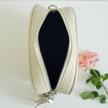 Lataa kuva Galleria-katseluun, ANGIE olkalaukussa on kaksi säädettävää olkahihnaa ja vetoketjukiinnitys. Tupsukoriste toimii vetimenä. Suosittu crossbody malli. Laukussa yski tasku ja pieni avotasku ja tekstiilivuorikangas. Materiaali: nahkaa Väri: luonnonvalkoinen Koko: pituus 20 cm, korkeus 15 cm, syvyys 7 cm.