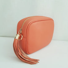 Lataa kuva Galleria-katseluun, Oranssi ANGIE olkalaukku on aitoa nahkaa. Laukussa on kaksi säädettävää olkahihnaa ja vetoketjukiinnitys. Tupsukoriste toimii vetimenä. Suosittu crossbody malli.