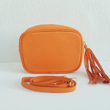Lataa kuva Galleria-katseluun, Oranssi ANGIE olkalaukku on aitoa nahkaa. Laukussa on kaksi säädettävää olkahihnaa ja vetoketjukiinnitys. Tupsukoriste toimii vetimenä. Suosittu crossbody malli.