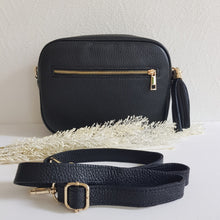 Lataa kuva Galleria-katseluun, BETTIE olkalaukku on aitoa nahkaa. Laukussa on säädettävä olkahihna, vetoketjukiinnitys ja vetoketjullinen takatasku. Tupsukoriste toimii vetimenä. Suosittu crossbody malli. Väri: musta, kullanvärisillä metallilukoilla.