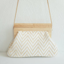 Lataa kuva Galleria-katseluun, Laukun kuviossa on siksak-kuosi, joka tuo siihen elävyyttä. Vaaleampi versio on beigen ja kullan sävyinen, kun taas tummempi on mustavalkoinen. Laukku näyttää tyylikkäältä ja sopii hyvin kesäkäyttöön.