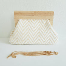 Lataa kuva Galleria-katseluun, Laukun kuviossa on siksak-kuosi, joka tuo siihen elävyyttä. Vaaleampi versio on beigen ja kullan sävyinen, kun taas tummempi on mustavalkoinen. Laukku näyttää tyylikkäältä ja sopii hyvin kesäkäyttöön.