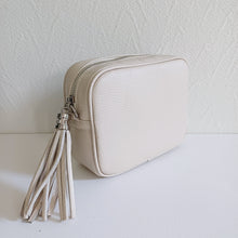 Lataa kuva Galleria-katseluun, ANGIE olkalaukku on aitoa nahkaa. Laukussa on säädettävä olkahihna ja vetoketjukiinnitys. Tupsukoriste toimii vetimenä. Suosittu cross body malli. Väri: musta Koko: pituus 20 cm, korkeus 15 cm, syvyys 7 cm. Olkahihnan pituus 130 cm. Hoito-ohje: Voi suojata nahalle sopivalla suojausaineella ennen käyttöönottoa. Puhdistetaan kostealla liinalla. Valmistusmaa Italia