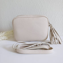 Lataa kuva Galleria-katseluun, ANGIE olkalaukku on aitoa nahkaa. Laukussa on säädettävä olkahihna ja vetoketjukiinnitys. Tupsukoriste toimii vetimenä. Suosittu cross body malli. Väri: musta Koko: pituus 20 cm, korkeus 15 cm, syvyys 7 cm. Olkahihnan pituus 130 cm. Hoito-ohje: Voi suojata nahalle sopivalla suojausaineella ennen käyttöönottoa. Puhdistetaan kostealla liinalla. Valmistusmaa Italia