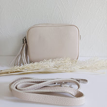 Lataa kuva Galleria-katseluun, ANGIE olkalaukku on aitoa nahkaa. Laukussa on säädettävä olkahihna ja vetoketjukiinnitys. Tupsukoriste toimii vetimenä. Suosittu cross body malli. Väri: musta Koko: pituus 20 cm, korkeus 15 cm, syvyys 7 cm. Olkahihnan pituus 130 cm. Hoito-ohje: Voi suojata nahalle sopivalla suojausaineella ennen käyttöönottoa. Puhdistetaan kostealla liinalla. Valmistusmaa Italia