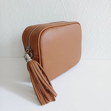 Lataa kuva Galleria-katseluun, ANGIE olkalaukku on aitoa nahkaa. Laukussa on säädettävä olkahihna ja vetoketjukiinnitys. Tupsukoriste toimii vetimenä. Suosittu cross body malli. Väri: ruskea Koko: pituus 20 cm, korkeus 15 cm, syvyys 7 cm. Olkahihnan pituus 130 cm. Hoito-ohje: Voi suojata nahalle sopivalla suojausaineella ennen käyttöönottoa. Puhdistetaan kostealla liinalla. Valmistusmaa Italia