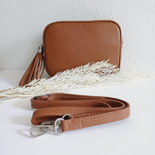 Lataa kuva Galleria-katseluun, ANGIE olkalaukku on aitoa nahkaa. Laukussa on säädettävä olkahihna ja vetoketjukiinnitys. Tupsukoriste toimii vetimenä. Suosittu cross body malli. Väri: ruskea Koko: pituus 20 cm, korkeus 15 cm, syvyys 7 cm. Olkahihnan pituus 130 cm. Hoito-ohje: Voi suojata nahalle sopivalla suojausaineella ennen käyttöönottoa. Puhdistetaan kostealla liinalla. Valmistusmaa Italia