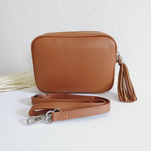 Lataa kuva Galleria-katseluun, ANGIE olkalaukku on aitoa nahkaa. Laukussa on säädettävä olkahihna ja vetoketjukiinnitys. Tupsukoriste toimii vetimenä. Suosittu cross body malli. Väri: ruskea Koko: pituus 20 cm, korkeus 15 cm, syvyys 7 cm. Olkahihnan pituus 130 cm. Hoito-ohje: Voi suojata nahalle sopivalla suojausaineella ennen käyttöönottoa. Puhdistetaan kostealla liinalla. Valmistusmaa Italia