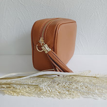 Lataa kuva Galleria-katseluun, ANGIE olkalaukussa on kaksi säädettävää olkahihnaa ja vetoketjukiinnitys. Tupsukoriste toimii vetimenä. Suosittu crossbody malli. Materiaali: aitoa nahkaa Väri: konjakinruskea