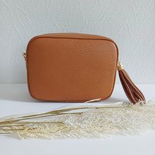 Lataa kuva Galleria-katseluun, ANGIE olkalaukussa on kaksi säädettävää olkahihnaa ja vetoketjukiinnitys. Tupsukoriste toimii vetimenä. Suosittu crossbody malli. Materiaali: aitoa nahkaa Väri: konjakinruskea