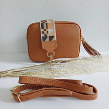 Lataa kuva Galleria-katseluun, ANGIE olkalaukussa on kaksi säädettävää olkahihnaa ja vetoketjukiinnitys. Tupsukoriste toimii vetimenä. Suosittu crossbody malli. Materiaali: aitoa nahkaa Väri: konjakinruskea