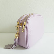 Lataa kuva Galleria-katseluun, Tyylikäs ja tilava LILY crossbody laukku on jaettu kolmeen osastoon. Jokainen osasto suljetaan vetoketjulla. Laukun takaa löytyy vetoketjullinen piilotasku ja sisällä on yksi vetoketjullinen sivutasku. Säädettävä olkahihna, kullanväriset metalliosat. Väri: vaalea lila