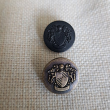 Lataa kuva Galleria-katseluun, Näyttävä muovinen metallipinnoitettu vaakunanappi kannalla, kaksi väriä: vanha kulta ja matta musta. Vaakunassa on sudet ja kilpi. Nappi sopii erityisesti klubitakkeihin, villakangastakkeihin, pitkiin neuleisiin, bleisereihin/ jakkuihin ja koristenapiksi
