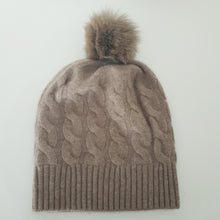 Lataa kuva Galleria-katseluun, TAIKA on upea 100 % kashmirista valmistettu palmikkoneulospipo, jota koristaa aito pörröinen tupsu. Pehmeä ja lämmin materiaali tuntuu miellyttävältä ihoa vasten, ja joustava malli takaa erinomaisen istuvuuden. Klassinen ribbineulos tekee piposta tyylikkään valinnan niin arkeen kuin juhlavampaankin talvityyliin.