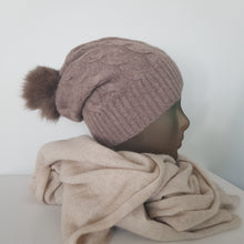 Lataa kuva Galleria-katseluun, TAIKA on upea 100 % kashmirista valmistettu palmikkoneulospipo, jota koristaa aito pörröinen tupsu. Pehmeä ja lämmin materiaali tuntuu miellyttävältä ihoa vasten, ja joustava malli takaa erinomaisen istuvuuden. Klassinen ribbineulos tekee piposta tyylikkään valinnan niin arkeen kuin juhlavampaankin talvityyliin.