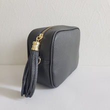 Lataa kuva Galleria-katseluun, ANGIE olkalaukku on aitoa nahkaa. Laukussa on kaksi säädettävää olkahihnaa ja vetoketjukiinnitys. Tupsukoriste toimii vetimenä. Suosittu crossbody malli. Väri: tummanharmaa Koko: pituus 20 cm, korkeus 15 cm, syvyys 7 cm. Laukkuun kuuluu kaksi säädettävää olkahihnaa: kapea nahkahihna kullanvärisillä pistolukoilla, leveys 2 cm, säädettävä pituus 128 cm leveä koristeellinen polyesteri/nahka hihna kullanvärisillä pistolukoilla, leveys 5,5 cm, säädettävä pituus max. 128 cm