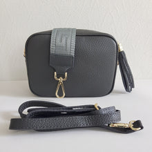 Lataa kuva Galleria-katseluun, ANGIE olkalaukku on aitoa nahkaa. Laukussa on kaksi säädettävää olkahihnaa ja vetoketjukiinnitys. Tupsukoriste toimii vetimenä. Suosittu crossbody malli. Väri: tummanharmaa Koko: pituus 20 cm, korkeus 15 cm, syvyys 7 cm. Laukkuun kuuluu kaksi säädettävää olkahihnaa: kapea nahkahihna kullanvärisillä pistolukoilla, leveys 2 cm, säädettävä pituus 128 cm leveä koristeellinen polyesteri/nahka hihna kullanvärisillä pistolukoilla, leveys 5,5 cm, säädettävä pituus max. 128 cm