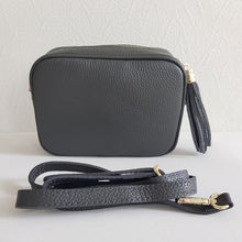 Lataa kuva Galleria-katseluun, ANGIE olkalaukku on aitoa nahkaa. Laukussa on kaksi säädettävää olkahihnaa ja vetoketjukiinnitys. Tupsukoriste toimii vetimenä. Suosittu crossbody malli. Väri: tummanharmaa Koko: pituus 20 cm, korkeus 15 cm, syvyys 7 cm. Laukkuun kuuluu kaksi säädettävää olkahihnaa: kapea nahkahihna kullanvärisillä pistolukoilla, leveys 2 cm, säädettävä pituus 128 cm leveä koristeellinen polyesteri/nahka hihna kullanvärisillä pistolukoilla, leveys 5,5 cm, säädettävä pituus max. 128 cm