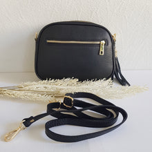 Lataa kuva Galleria-katseluun, Tyylikäs ja tilava LILY crossbody laukku on jaettu kolmeen osastoon. Jokainen osasto suljetaan vetoketjulla. Laukun takaa löytyy vetoketjullinen piilotasku ja sisällä on yksi vetoketjullinen sivutasku. Säädettävä olkahihna, kullanväriset metalliosat. Väri: musta Koko: pituus 23 cm, korkeus 16.6 cm, syvyys 7 cm Olkahihna: leveys 1.5 cm, max pituus 135 cm. Leveä koristeellinen polyesteri/ nahka hihna kullanvärisillä pistolukoilla, leveys 5,5 cm, säädettävä pituus max. 128 cm