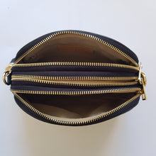 Lataa kuva Galleria-katseluun, Tyylikäs ja tilava LILY crossbody laukku on jaettu kolmeen osastoon. Jokainen osasto suljetaan vetoketjulla. Laukun takaa löytyy vetoketjullinen piilotasku ja sisällä on yksi vetoketjullinen sivutasku. Säädettävä olkahihna, kullanväriset metalliosat. Väri: musta Koko: pituus 23 cm, korkeus 16.6 cm, syvyys 7 cm Olkahihna: leveys 1.5 cm, max pituus 135 cm. Leveä koristeellinen polyesteri/ nahka hihna kullanvärisillä pistolukoilla, leveys 5,5 cm, säädettävä pituus max. 128 cm