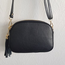 Lataa kuva Galleria-katseluun, Tyylikäs ja tilava LILY crossbody laukku on jaettu kolmeen osastoon. Jokainen osasto suljetaan vetoketjulla. Laukun takaa löytyy vetoketjullinen piilotasku ja sisällä on yksi vetoketjullinen sivutasku. Säädettävä olkahihna, kullanväriset metalliosat. Väri: musta Koko: pituus 23 cm, korkeus 16.6 cm, syvyys 7 cm Olkahihna: leveys 1.5 cm, max pituus 135 cm. Leveä koristeellinen polyesteri/ nahka hihna kullanvärisillä pistolukoilla, leveys 5,5 cm, säädettävä pituus max. 128 cm