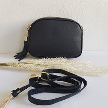 Lataa kuva Galleria-katseluun, Tyylikäs ja tilava LILY crossbody laukku on jaettu kolmeen osastoon. Jokainen osasto suljetaan vetoketjulla. Laukun takaa löytyy vetoketjullinen piilotasku ja sisällä on yksi vetoketjullinen sivutasku. Säädettävä olkahihna, kullanväriset metalliosat. Väri: musta Koko: pituus 23 cm, korkeus 16.6 cm, syvyys 7 cm Olkahihna: leveys 1.5 cm, max pituus 135 cm. Leveä koristeellinen polyesteri/ nahka hihna kullanvärisillä pistolukoilla, leveys 5,5 cm, säädettävä pituus max. 128 cm