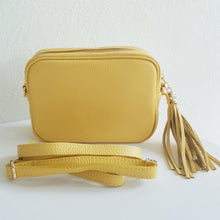 Lataa kuva Galleria-katseluun, ANGIE olkalaukku on aitoa nahkaa. Laukussa on säädettävä olkahihna, vetoketjukiinnitys. Tupsukoriste toimii vetimenä. Valmistettu Italiassa, erittäin suosittu cross body malli. Väri: keltainen Koko: pituus 20 cm, korkeus 15 cm, syvyys 7 cm. Olkahihnan pituus 130 cm. Hoito-ohje: Voi suojata nahalle sopivalla suojausaineella ennen käyttöönottoa. Puhdistetaan kostealla liinalla.