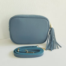 Lataa kuva Galleria-katseluun, ANGIE olkalaukku on aitoa nahkaa. Väri: harmaansininen Koko: pituus 20 cm, korkeus 15 cm, syvyys 7 cm. Laukkuun kuulu kaksi säädettävää olkahihnaa: kapea nahkahihna kullanvärisillä pistolukoilla, leveys 2 cm, säädettävä pituus 130 cm leveä koristeellinen polyesteri/ nahka hihna kullanvärisillä pistolukoilla, leveys 5,5 cm, säädettävä pituus max. 128 cm Hoito-ohje: Voi suojata nahalle sopivalla suojausaineella ennen käyttöönottoa. Puhdistetaan kostealla liinalla.