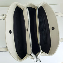 Lataa kuva Galleria-katseluun, Tilava BELINDA nahkalaukku on tyylikäs ja ajaton, suunniteltu klassiseen tyyliin. Laukussa on kaksi pyöristettyä kantokahvaa ja mukana on myös irrotettava, ohut olkahihna, jonka avulla laukkua voi kantaa olkapäällä tai crossbody-tyyliin. Laukussa on kolme erillistä osastoa: keskellä iso vetoketjullinen osasto ja sen molemmilla puolilla osastot magneettilukituksella. Sisältä löytyy lisäksi pieni vetoketjullinen sivutasku ja kaksi pientä avotaskua. Väri: luonnonvalkoinen, tummanhopeat (gunmetal) metalliosat