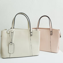 Lataa kuva Galleria-katseluun, Tilava BELINDA nahkalaukku on tyylikäs ja ajaton, suunniteltu klassiseen tyyliin. Laukussa on kaksi pyöristettyä kantokahvaa ja mukana on myös irrotettava, ohut olkahihna, jonka avulla laukkua voi kantaa olkapäällä tai crossbody-tyyliin. Laukussa on kolme erillistä osastoa: keskellä iso vetoketjullinen osasto ja sen molemmilla puolilla osastot magneettilukituksella. Sisältä löytyy lisäksi pieni vetoketjullinen sivutasku ja kaksi pientä avotaskua. Väri: luonnonvalkoinen, tummanhopeat (gunmetal) metalliosat.