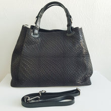 Lataa kuva Galleria-katseluun, Upea CHIARA laukku on tunnetun Bottega Veneta brändin inspiroima malli. Tyylikäs ja tilava laukku on valmistettu aidosta intrecciato punotusta nahasta. Sisällä on vetoketjullinen tilanjakaja sekä vetoketjullinen sivutasku ja avotasku. Väri: musta Kantokahvat ja olkahihna voi säätää. Koko: korkeus 32 cm, leveys 50 cm, syvyys 19 cm Olkahihnan koko: leveys 2 cm, max pituus 125 cm Valmistettu Italiassa.