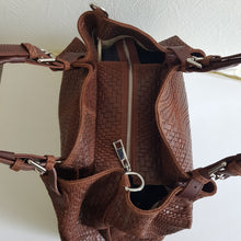 Lataa kuva Galleria-katseluun, Upea CHIARA laukku on tunnetun Bottega Veneta brändin inspiroima malli. Tyylikäs ja tilava laukku on valmistettu aidosta intrecciato punotusta nahasta. Sisällä on vetoketjullinen tilanjakaja sekä vetoketjullinen sivutasku sekä avotasku Väri: ruskea Kantokahvat ja olkahihna on säädettävät. Koko: korkeus 32 cm, leveys 50 cm, syvyys 19 cm Olkahihnan koko: leveys 2 cm, max pituus 125 cm Valmistettu Italiassa.