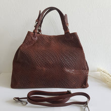 Lataa kuva Galleria-katseluun, Upea CHIARA laukku on tunnetun Bottega Veneta brändin inspiroima malli. Tyylikäs ja tilava laukku on valmistettu aidosta intrecciato punotusta nahasta. Sisällä on vetoketjullinen tilanjakaja sekä vetoketjullinen sivutasku sekä avotasku Väri: ruskea Kantokahvat ja olkahihna on säädettävät. Koko: korkeus 32 cm, leveys 50 cm, syvyys 19 cm Olkahihnan koko: leveys 2 cm, max pituus 125 cm Valmistettu Italiassa.