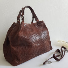 Lataa kuva Galleria-katseluun, Upea CHIARA laukku on tunnetun Bottega Veneta brändin inspiroima malli. Tyylikäs ja tilava laukku on valmistettu aidosta intrecciato punotusta nahasta. Sisällä on vetoketjullinen tilanjakaja sekä vetoketjullinen sivutasku sekä avotasku Väri: ruskea Kantokahvat ja olkahihna on säädettävät. Koko: korkeus 32 cm, leveys 50 cm, syvyys 19 cm. Olkahihnan koko: leveys 2 cm, max pituus 125 cm Valmistettu Italiassa.