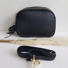 Lataa kuva Galleria-katseluun, Tyylikäs ja tilava LILY crossbody laukku on jaettu kolmeen osastoon. Jokainen osasto suljetaan vetoketjulla. Laukun takaa löytyy vetoketjullinen piilotasku ja sisällä on yksi vetoketjullinen sivutasku. Säädettävä olkahihna, kullanväriset metalliosat. Väri: musta