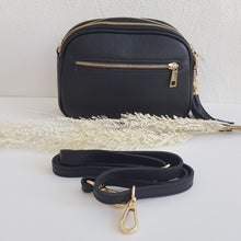 Lataa kuva Galleria-katseluun, Tyylikäs ja tilava LILY crossbody laukku on jaettu kolmeen osastoon. Jokainen osasto suljetaan vetoketjulla. Laukun takaa löytyy vetoketjullinen piilotasku ja sisällä on yksi vetoketjullinen sivutasku. Säädettävä olkahihna, kullanväriset metalliosat. Väri: musta