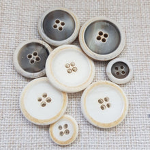 Lataa kuva Galleria-katseluun, Kaunis eläväpintainen orgaaninen nelireikäinen sarveisnappi. Napin valmistuksessa on käytetty ureaa mikä tekee napista vahvan ja kestää lämmön. Koot 15mm (paksuus 3.5 mm), 23 mm (paksuus 5 mm), 25mm (paksuus 5 mm). Värit valkobeige ja valkoharmaa. Sopii pikkutakkeihin, bleisereihin, nappimekkoihin, housuihin, hamenapiksi ja neulepuseroihin.