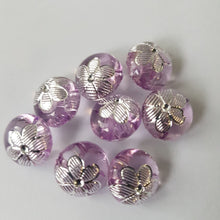 Lataa kuva Galleria-katseluun, Kauniit pienet KUKKA lasten napit. Napin pinnassa on hopea kukka ja nappi ommellaan takaa kiinni. Nappi sopii lasten neuleisiin ja koristeeksi esimerkiksi pipoihin. Napista löytyy viisi väriä: luonnonvalkoinen, vihreä, sininen, ruskea ja lila.