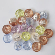 Lataa kuva Galleria-katseluun, Kauniit pienet KUKKA lasten napit. Napin pinnassa on hopea kukka ja nappi ommellaan takaa kiinni. Nappi sopii lasten neuleisiin ja koristeeksi esimerkiksi pipoihin. Napista löytyy viisi väriä: luonnonvalkoinen, vihreä, sininen, ruskea ja lila.