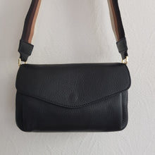 Lataa kuva Galleria-katseluun, Musta SANDRA on arjen varma kumppani. Klassinen musta nahka saa rennon ilmeen beige–ruskea–musta raidallisesta hihnasta, joka tekee laukusta monikäyttöisen ja trendikkään.