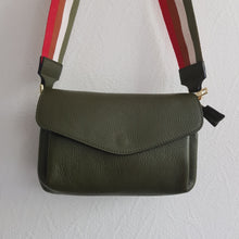 Lataa kuva Galleria-katseluun, Vihreä SANDRA tuo luonnonläheistä raikkautta arkeen. Punainen–oranssi–valkoinen–vihreä raidallinen hihna antaa laukulle energisen ja persoonallisen ilmeen. Sisäosa on jaettu kolmeen lokeroon: keskellä vetoketjullinen tasku ja reunoilla avotaskut, käytännöllinen rakenne tekee siitä täydellisen matkakumppanin.