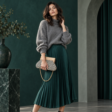 Lataa kuva Galleria-katseluun, Malli harmaassa neuleessa ja syvänvihreässä pliseroidussa hameessa pitelee mustavalkoista Emma clutch -laukkua, jossa on puinen kehys ja kullanvärinen ketjuhihna.
