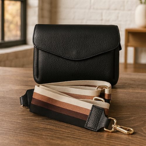 Rento musta crossbody-laukku, jossa beige–ruskea–musta raidallinen hihna. Kolme lokeroa, keskellä vetoketjullinen tasku – tavarat pysyvät järjestyksessä. Aitoa nahkaa, valmistettu Italiassa.
