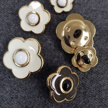 Lataa kuva Galleria-katseluun, Kannallinen muovinen KUKKA koristenappi. Napissa on kullanvärinen pohja kahdella värivaihtoehdolla: luonnonvalkoinen emali/ valkoinen keskus tai ruskea emali/ musta keskus. Koot 18 mm, 23 mm, 28 mm.
