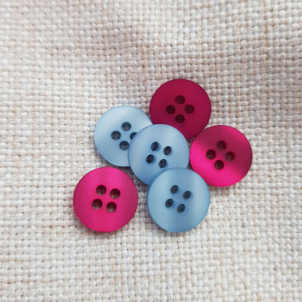 Läpiommeltava muovinen perus paitanappi, 12 mm, kaksi väriä: fuksia ja sininen. Sopii paitapseroihin, lastennapiksi, trikovaatteisiin.
